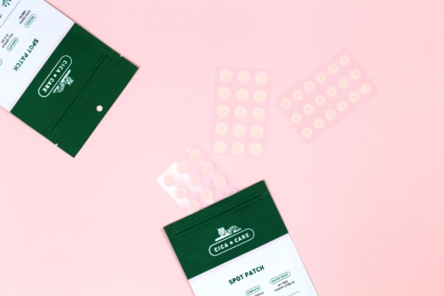 To grønne esker merket "Spot Patch" og noen runde plaster på en rosa bakgrunn.