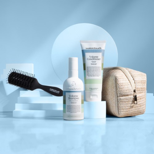 Hair care products, a brush, and a beige makeup bag on blue background with white steps.