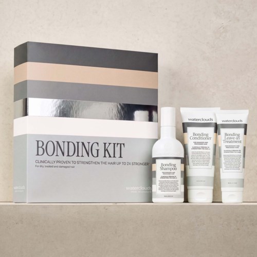 Bonding Kit mit Shampoo, Conditioner und Leave-In in weißen Flaschen und Tuben auf einem Regal.