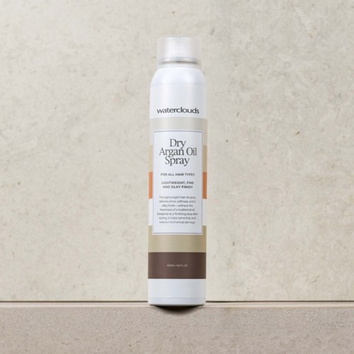 En vit sprayflaska märkt 'Waterclouds Dry Argan Oil Spray' står mot en enkel bakgrund.