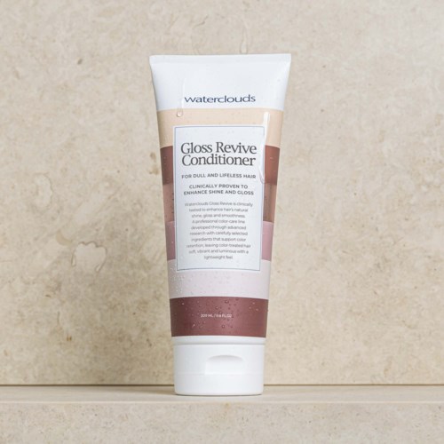 En vit tub med Waterclouds Gloss Revive Conditioner, rosa- och beigeetikett och vit lock, står på en beige yta.