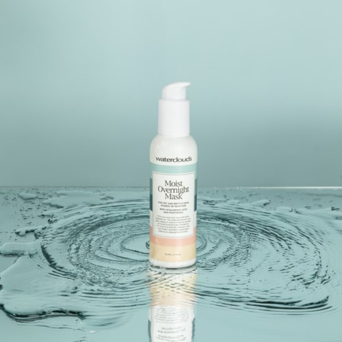 En vit pumpflaska märk med Moist Overnight Mask står på vatten, som skapar ringar med en ljusblå bakgrund.