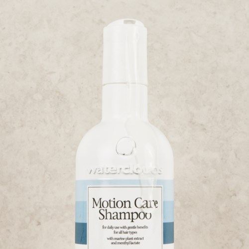 Valkoinen pullo pumppupäällä, jossa lukee 'Motion Care Shampoo'. Päivittäiseen käyttöön merikasvinuutteella.