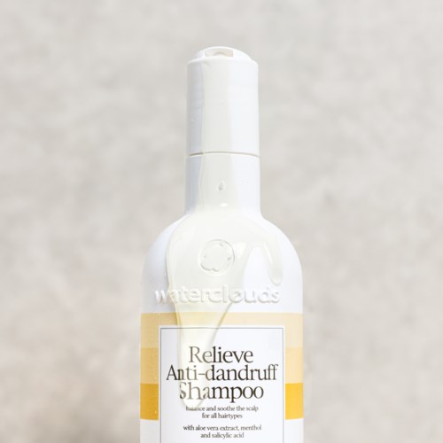 Eine weiße Sprayflasche mit einem Etikett, das 'Relieve Anti-dandruff Shampoo' sagt und einen gelben Streifen.