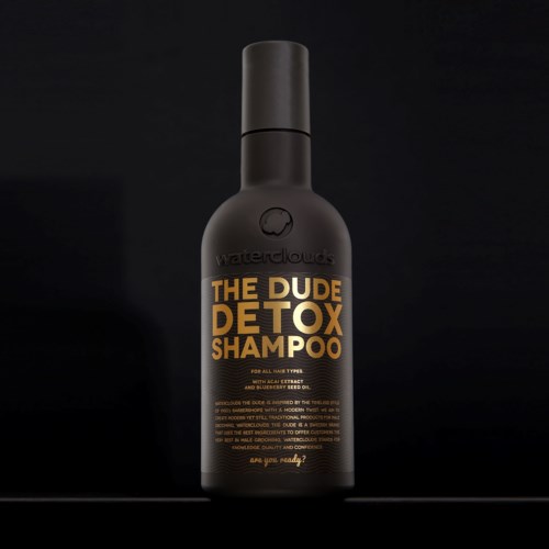 En svart flaska märkt 'The Dude Detox Shampoo' med guld- och vitt text, och ett svart lock.