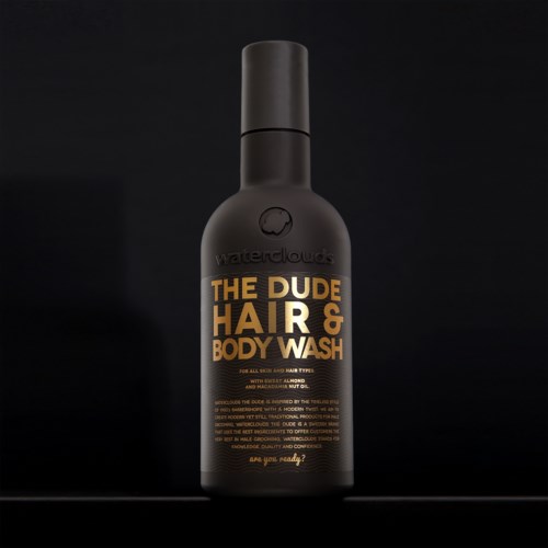 En svart flaske med Waterclouds The Dude Hair & Body Wash med orange og hvit tekst, står mot en svart bakgrunn.