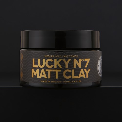 En svart krukke med gullfarget og hvit tekst som sier "Lucky N°7 Matt Clay" og informasjon om størrelse og opprinnelse.