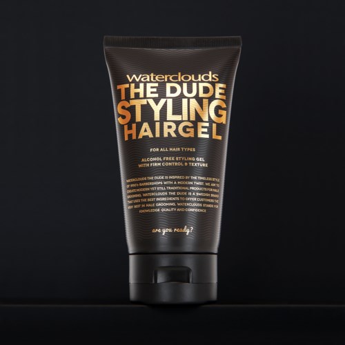 Eine schwarze Tube Waterclouds The Dude Styling Hair Gel mit orange und weißem Text, auf dunklem Hintergrund.