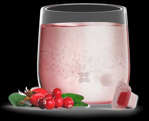 A glass of pink liquid with cranberry berries, a leaf, and a tea bag on a black background.