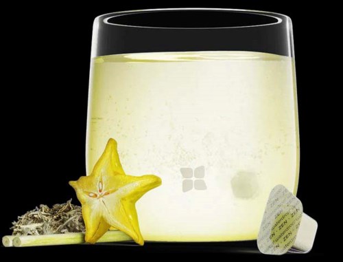 A glass with a pale yellow drink, star-shaped fruit and tea bag next to it, on a black background.