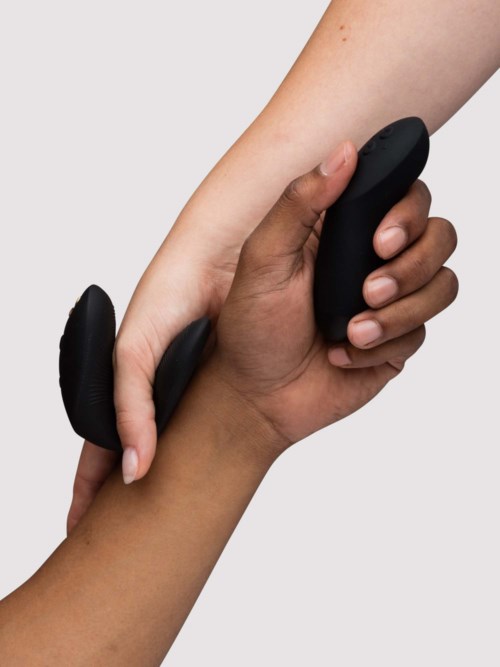 Närbild på en persons hand som håller en svart massager mot armen.