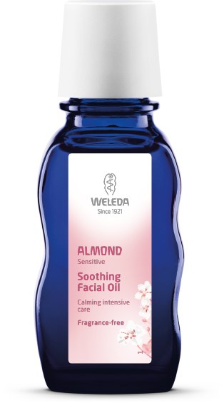 En marinblå flaska med Weleda mandel lugnande ansiktsolja med vit kork och rosa etikett.