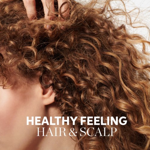 En kvinne har krøllete rødt hår, og teksten sier "Healthy Feeling Hair & Scalp."