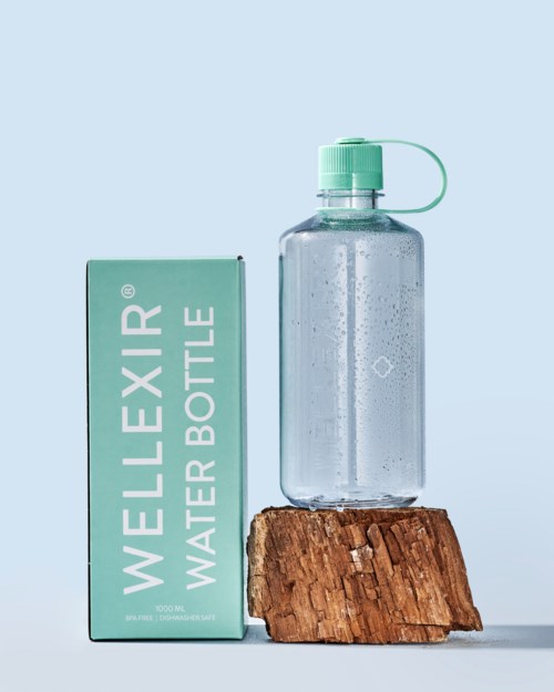 En klar vandflaske med grøn kapsel på en træblok, ved siden af en grøn boks mærket 'WELLEXIR WATER BOTTLE.'