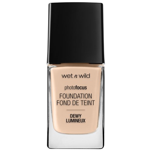 En flaske med Wet n Wild foundation med svart lokk, beige væske synlig inni, og produktinformasjon er skrevet på forsiden.