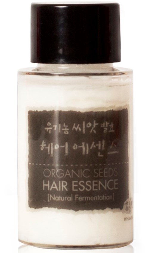 En liten flaska med svart lock innehållande hårvårdsprodukt märkt 'Organic Seeds Hair Essence'.