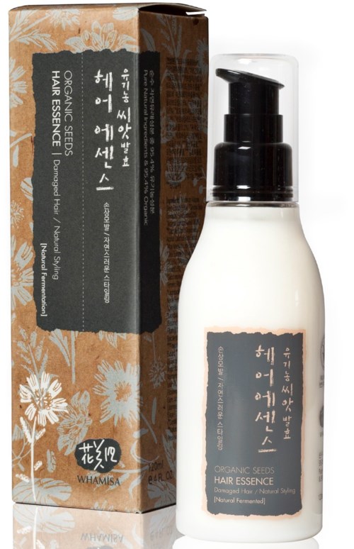 En vit flaska med pump, märkt 'Hair Essence' från ekologiska frön, bredvid en blomsterprydd låda.