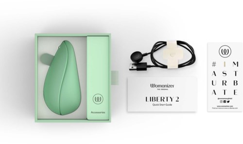 En grön enhet med laddningskabel, instruktion och ett kort med bokstäver och Womanizer-logotyp.