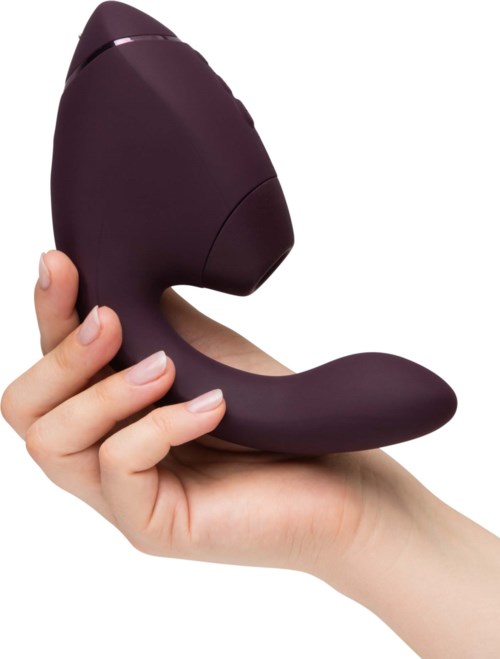 Eine Hand hält einen lilafarbenen, ergonomischen Personal Massager mit gebogenem Design und glatter Oberfläche.