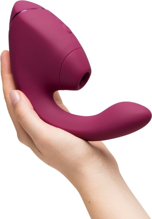Eine Hand hält ein lila, gebogenes Massagegerät mit rundem Kopf und Griff.