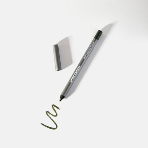 A green marker with its cap nearby, drawing a squiggly line on a white surface.