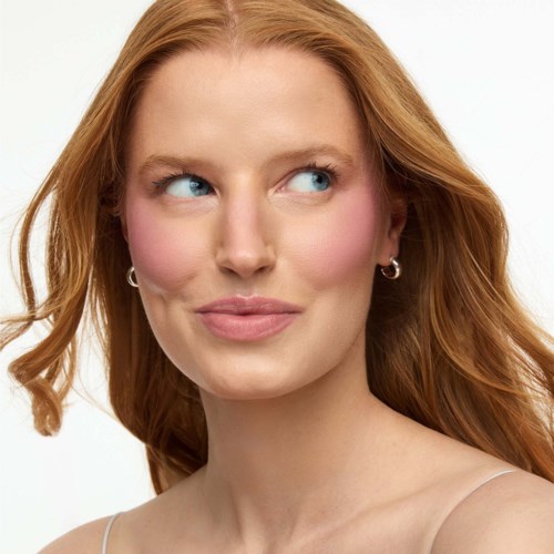 A woman with red hair and natural makeup looking to the side.