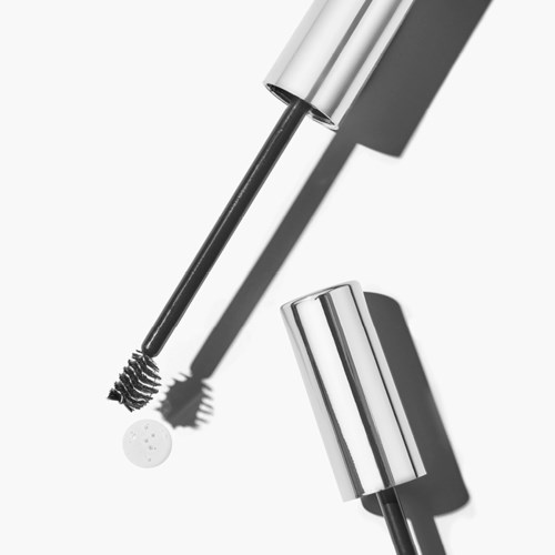 Eine Wimperntusche-Bürste mit weißem, silbernem und schwarzem Design und einem silbernen Deckel, auf weißem Hintergrund.