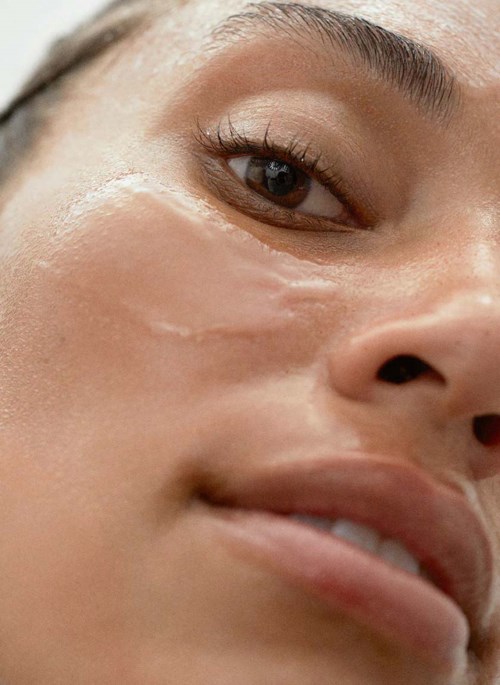 Close-up van een vrouwelijk gezicht met een gladde huid, donker oog en iets open lippen.