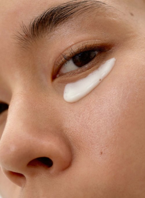 Een persoon heeft een witte crème onder hun oog, close-up foto, toont huid en deel van de neus.