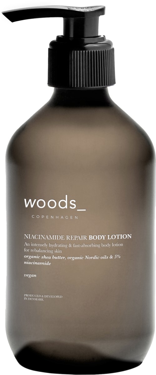 Een donker flesje met een pompdop met Woods-Copenhagen lichaamslotion, gemarkeerd als niacinamide herstel, voor huidvochtigheid.