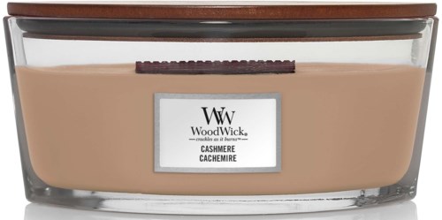 A glass jar with a brown lid, filled with beige colored cashmere-scented candle.