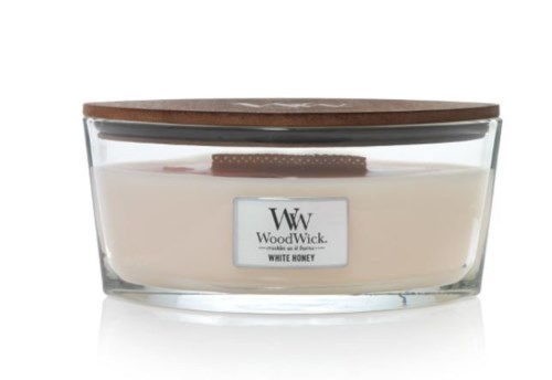 En glasskrukke med krem, sjokoladekjeks oppå, og et trelokk. Krukken har en etikett som sier WoodWick og White Honey.