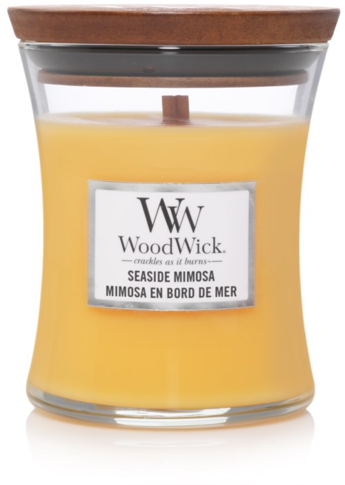 A yellow candle in a glass jar with a wooden lid and a label saying WoodWick Seaside Mimosa.