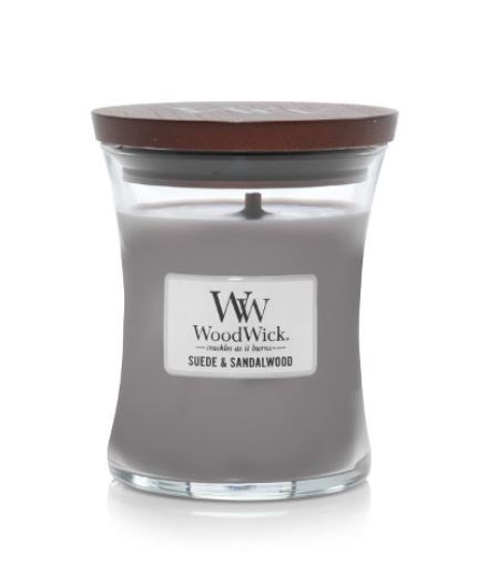 Eine Kerze in einem Glas mit braunem Deckel, beschriftet mit 'Wood Wick Suede & Sandalwood' Duft.