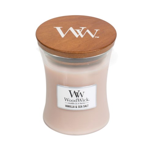 Et lys i en glasskål med trelokk har WoodWick-logo og duftetikett for vanilje og havsalt.