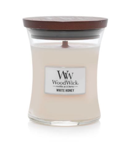Et hvitt lys i en glasskrukke med et brunt lokk, merket 'WoodWick White Honey'.
