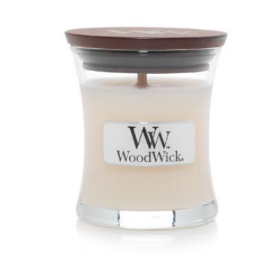Et lite lys i et glasskrukke med et treskruelokk. Etiketten sier WoodWick.