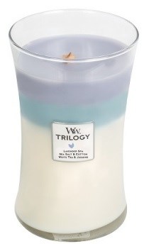 Et stearinlys i et glas med tre lag: hvidt, blåt og lilla, og en lille flamme ovenpå.