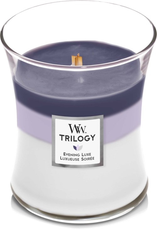 Et lys i glas med lilla og hvid farve og mærkat, der siger "Trilogy" og "Evening Luxe."