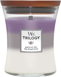 Ett doftljus i lila och vitt i en klar glasburk med lock av trä, märkt "Trilogy Amethyst Sky."