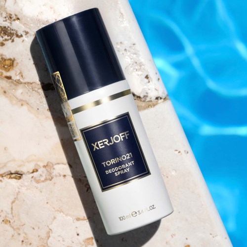 En deodorantsprayflaska märkt "XERJOFF" ligger på en kaklad yta nära en blå pool.