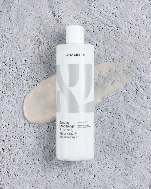 Grazette bonding conditioner för behandlat, krävande och svagt hår, med vit och grå flaska på en strukturerad yta.