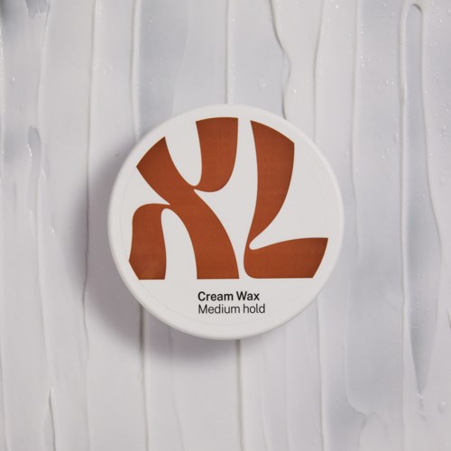 En rund beholder med hvitt lokk og brunt design, merket 'Cream Wax, Medium hold'.