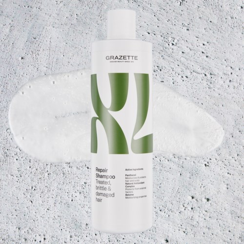 Bottle of Repair Shampoo for fragile, damaged hair, with a green and white label, on a textured surface.