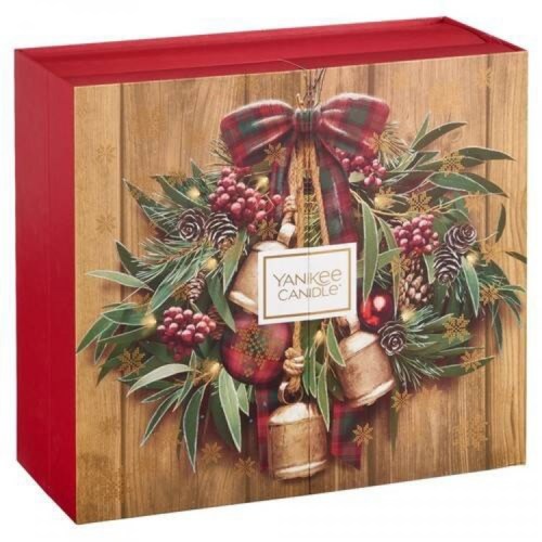 En röd låda dekorerad med en krans av blad, hasselnötter, bär, bjällror och en rosett, med en "Yankee Candle"-etikett.