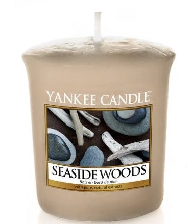 En beige duftlys med en etiket, der viser sten og drivved, kaldet Seaside Woods, med naturlige ekstrakter.