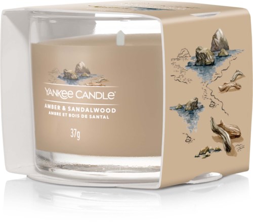 Ett värmeljus i klart glas med sand- och trädoftsomslag, dekorerat med små stenar och drivvedillustrationer.