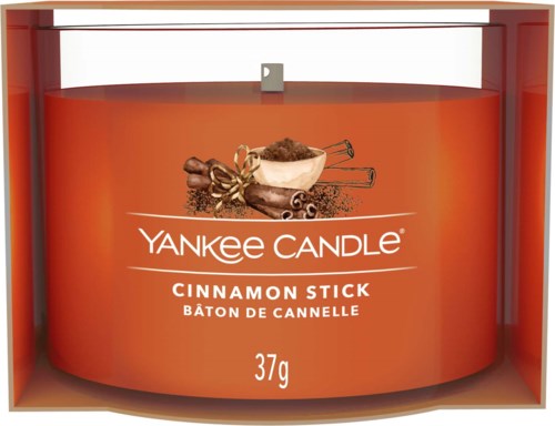 Et duftlys med kanel fra Yankee Candle, i en oransje beholder, med kanelstenger og krydder på etiketten.