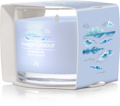 Ett ljus i ett box med havs- och molnmotiv, märkt "Yankee Candle Ocean Air," med en vit veke.