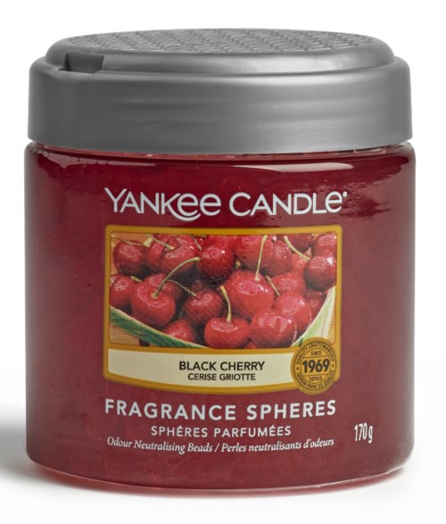 En rød krukke fra Yankee Candle med sølvlokk, merket 'Black Cherry' og 'Fragrance Spheres,' med kirsebær på etiketten.